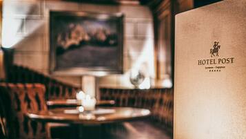 A blurred interior of a restaurant with a table and chairs, a candle, and a framed picture on the wall.