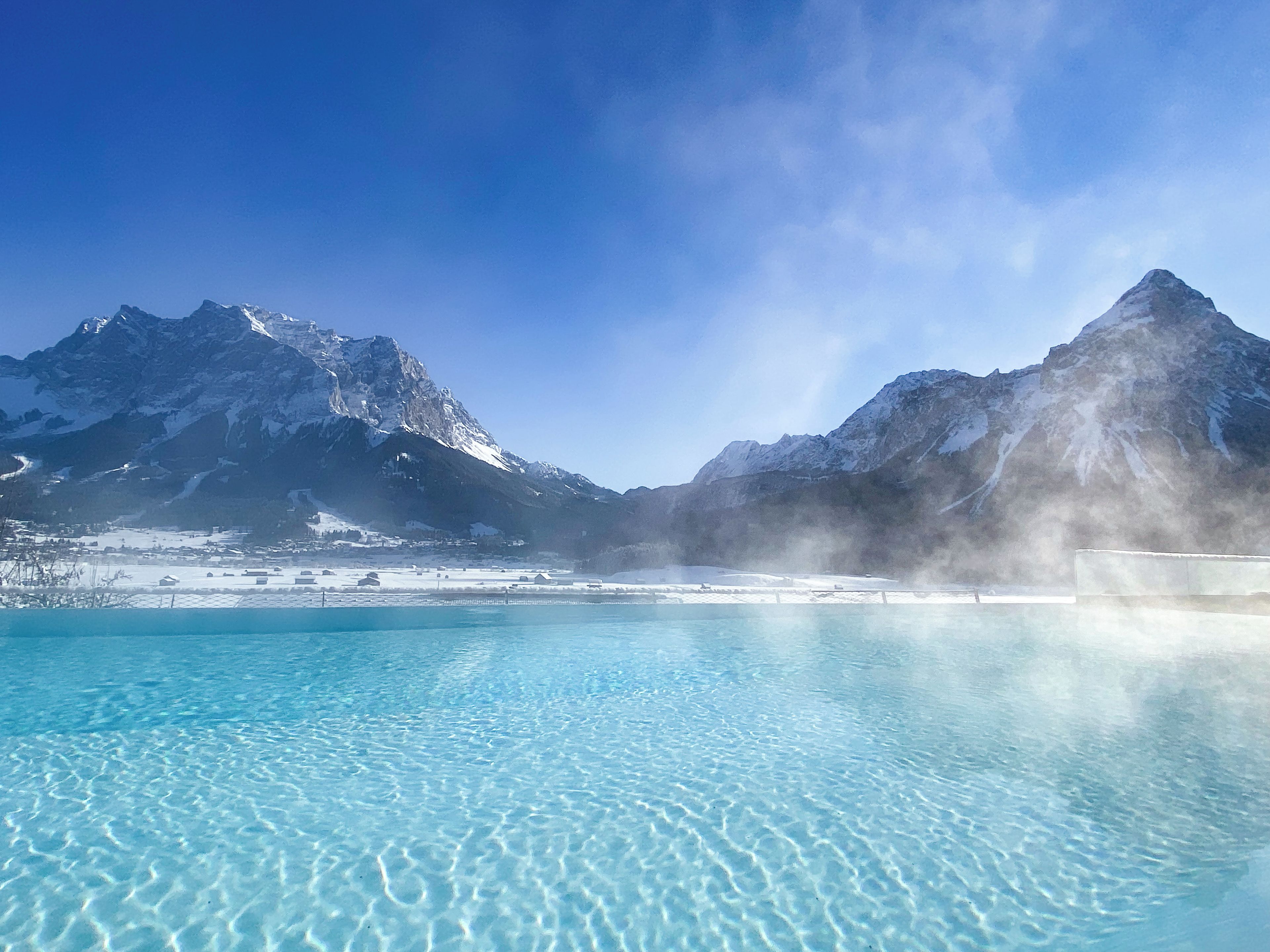 A clear blue pool with mountains in the background.