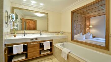 A modern bathroom with a large bathtub, a double sink vanity, and a large mirror.