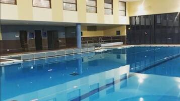 Una piscina al coperto con corsie ben delimitate, un trampolino e una scala.