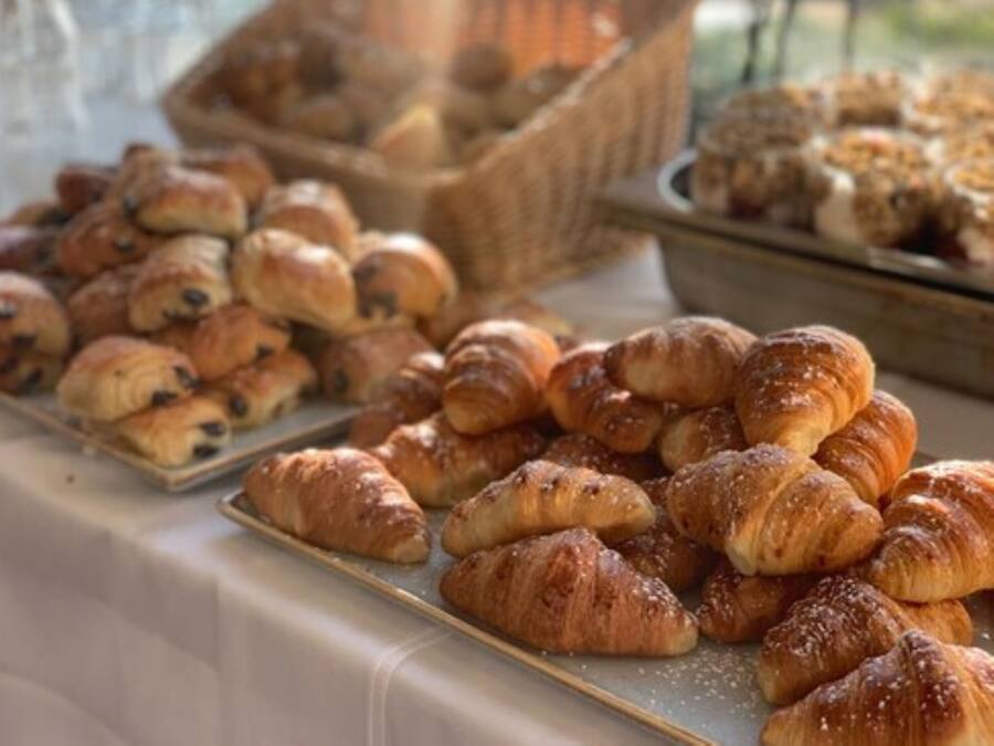 Una mesa con varios pasteles, incluyendo croissants y otras bollerías.
