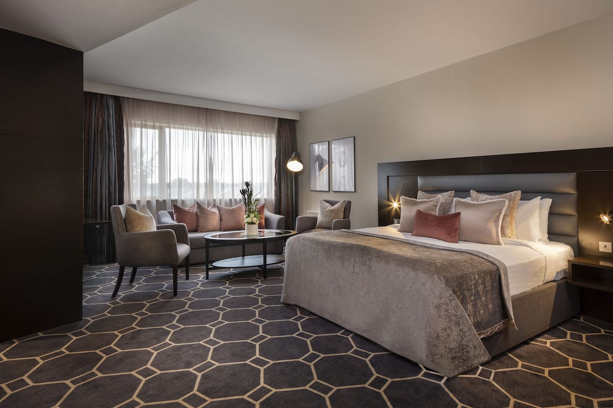 Ein Hotelzimmer mit einem großen Bett, einer Couch, einem Couchtisch und Blick ins Freie.