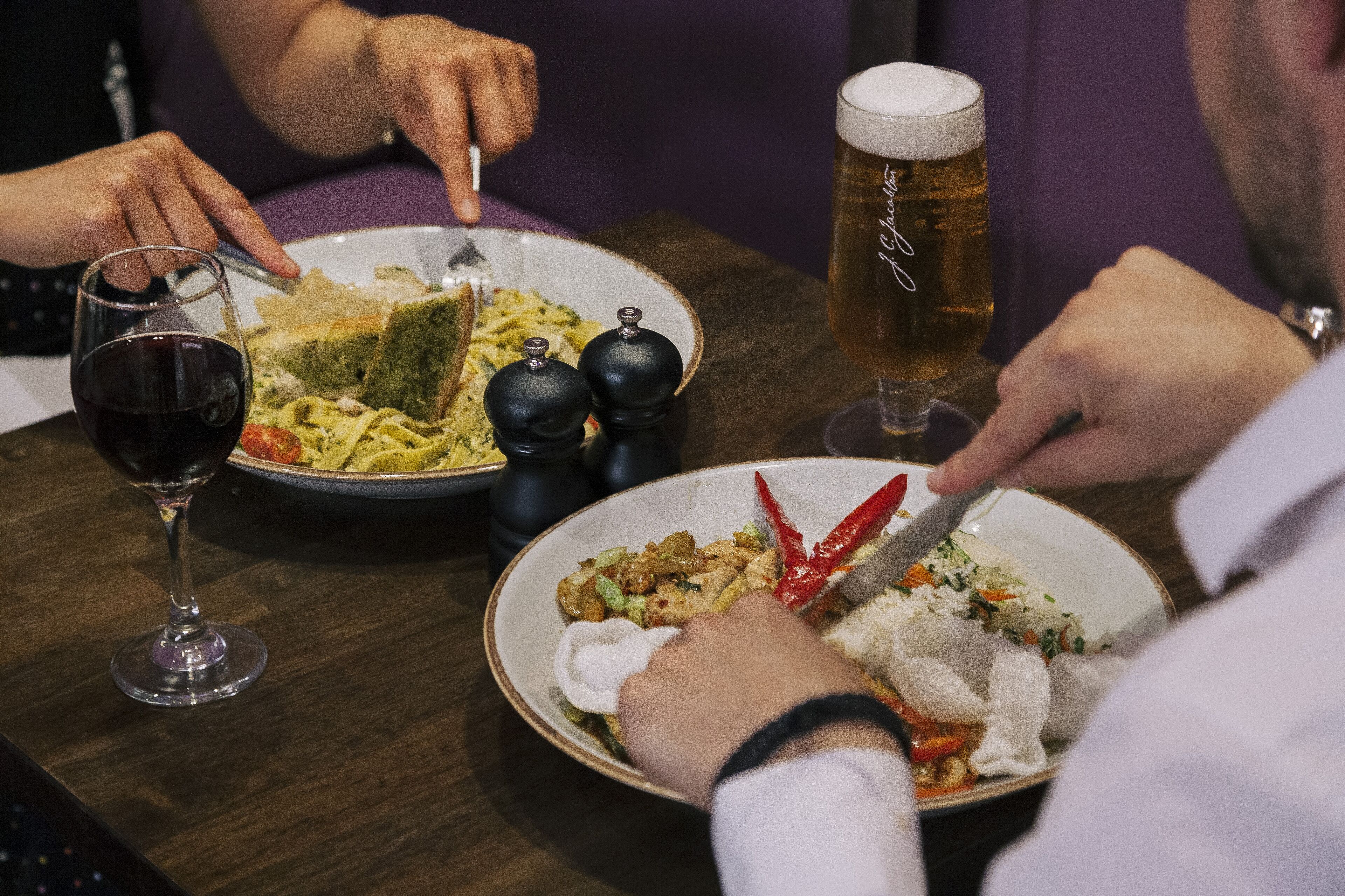 Una mesa con platos de comida, una jarra de cerveza y una copa de vino.