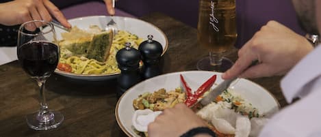 Una mesa con platos de comida, una jarra de cerveza y una copa de vino.