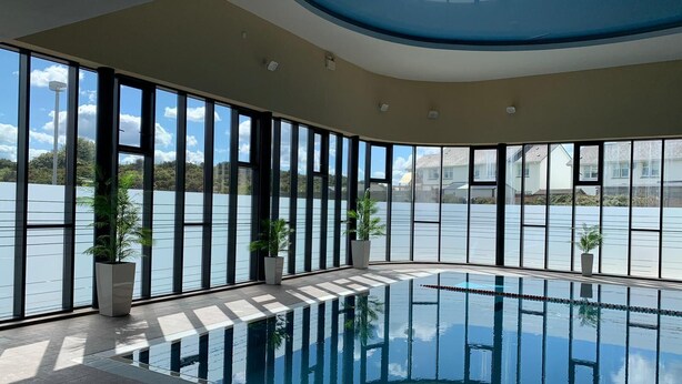 Una piscina interior moderna con ventanas amplias que ofrecen vistas a un lago.