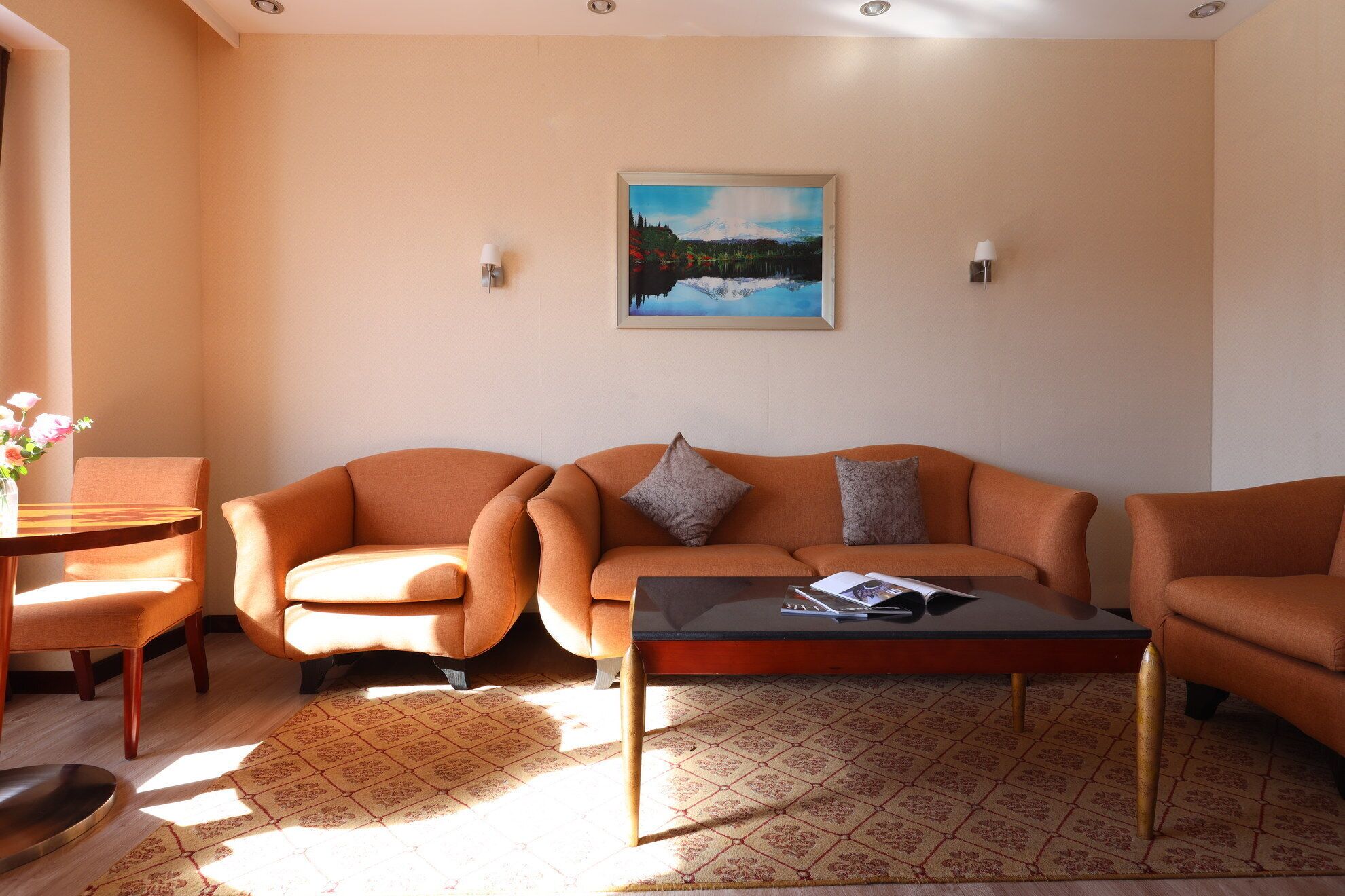 Ein Wohnzimmer mit einer Couch, Sesseln, einem Couchtisch und einem Gemälde an der Wand.