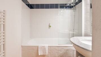 A modern bathroom with a glass-enclosed shower, a white sink, and a towel rack.