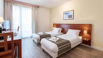 A hotel room with two beds, a desk, and a chair.
