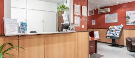 En reception med en trædisk, en digital informationsskærm og et stort spejl.