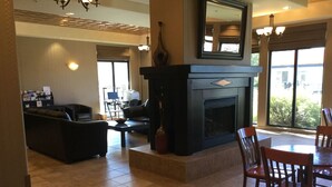 Amplia sala de estar con chimenea, asientos cómodos y un comedor con sillas de madera.