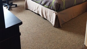 Habitación de hotel con cama, escritorio, silla, mesita de noche y lámpara de pared.