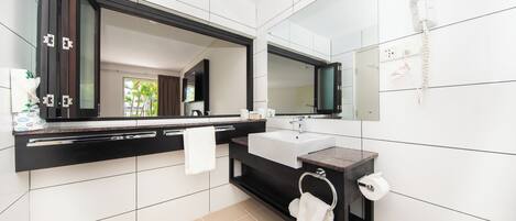 Un baño moderno con un espejo grande, azulejos blancos, un tocador negro y una ducha.