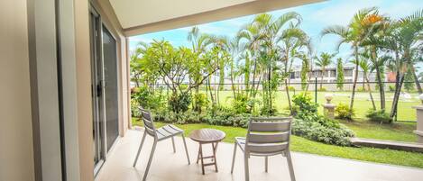 Ein Balkon mit Blick auf einen gepflegten Garten und Palmen.