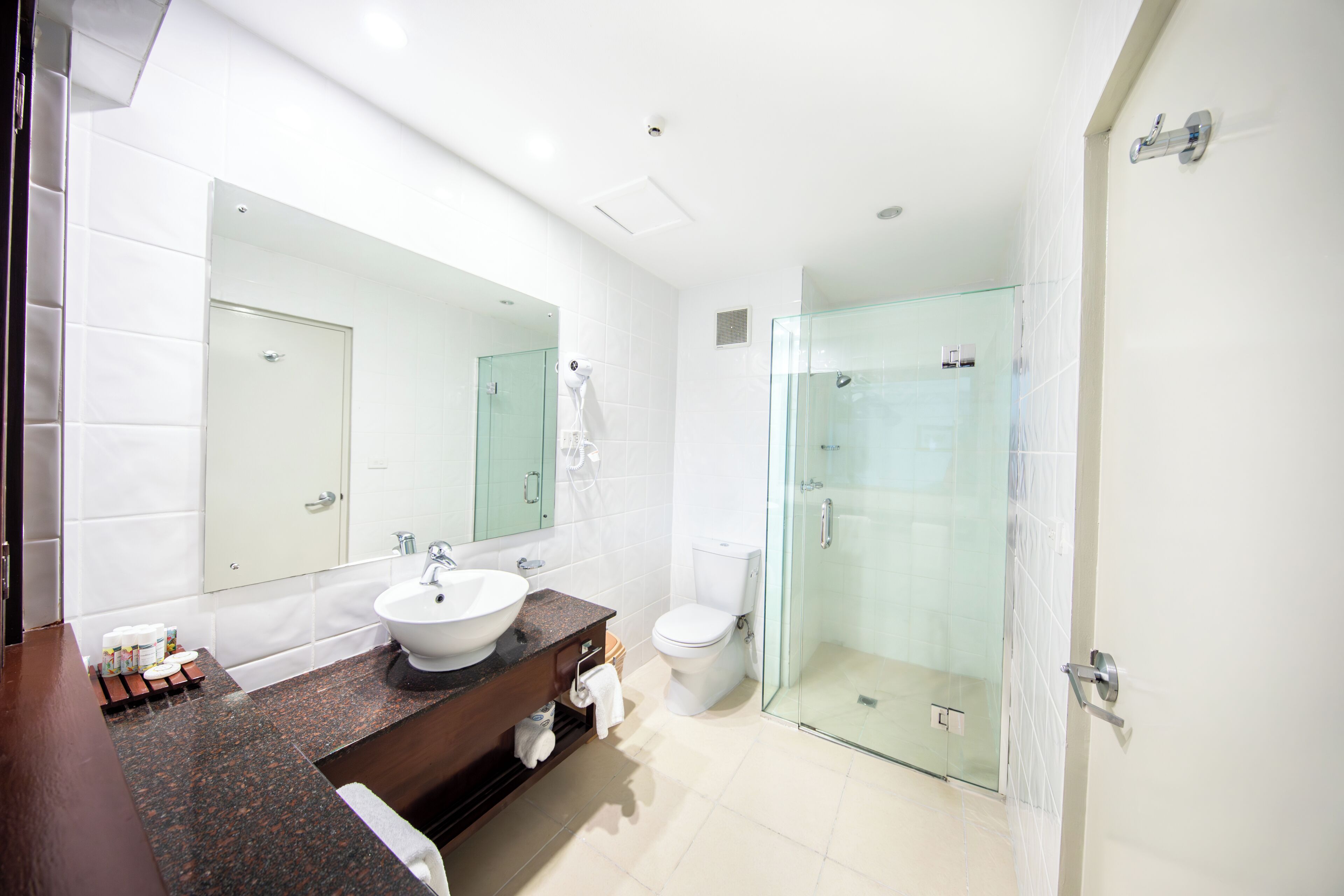 Une salle de bain moderne avec une douche à parois de verre, un grand miroir et un lavabo blanc.