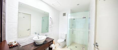 Une salle de bain moderne avec une douche à parois de verre, un grand miroir et un lavabo blanc.