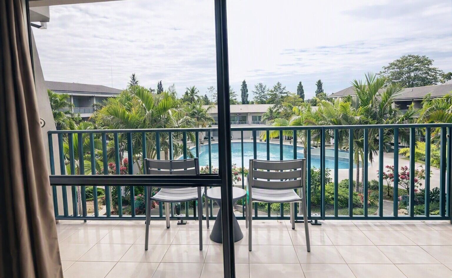Varanda com vista para uma piscina, rodeada por vegetação e um cercado.