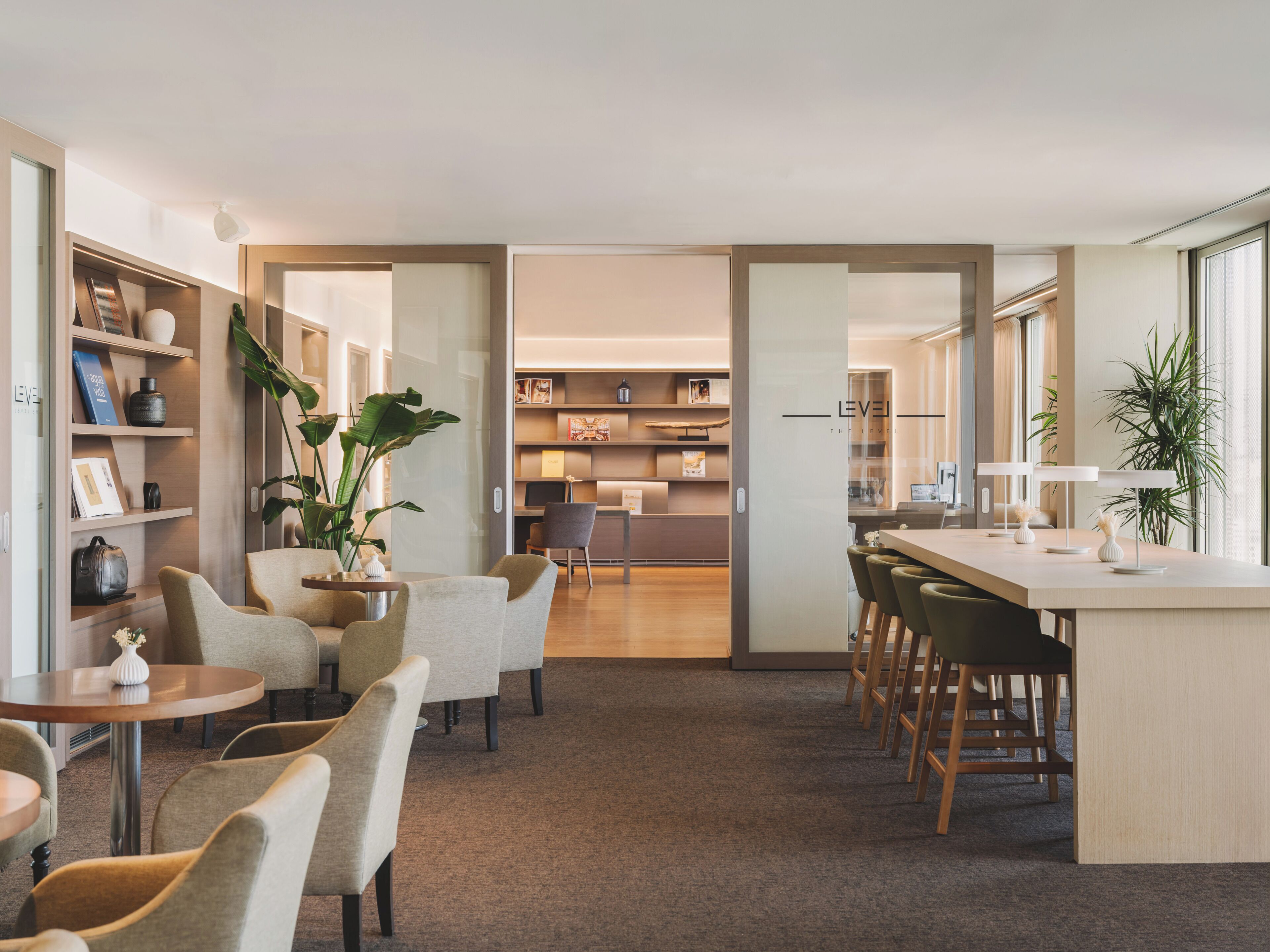 Un moderno vestíbulo de hotel con una zona de estar, una recepción y vistas al comedor.