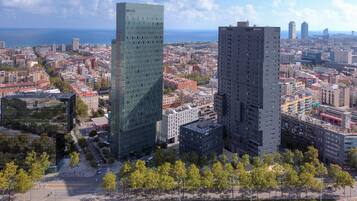 A cityscape with modern high-rise buildings, a clear sky, and a distant view of the sea.