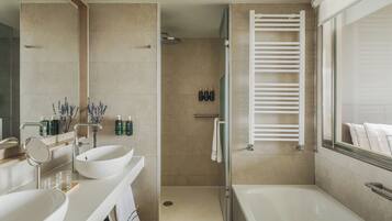 Une salle de bain moderne dotée d’une grande baignoire, d’une douche à l’italienne et d’un meuble-lavabo avec un miroir et deux vasques.