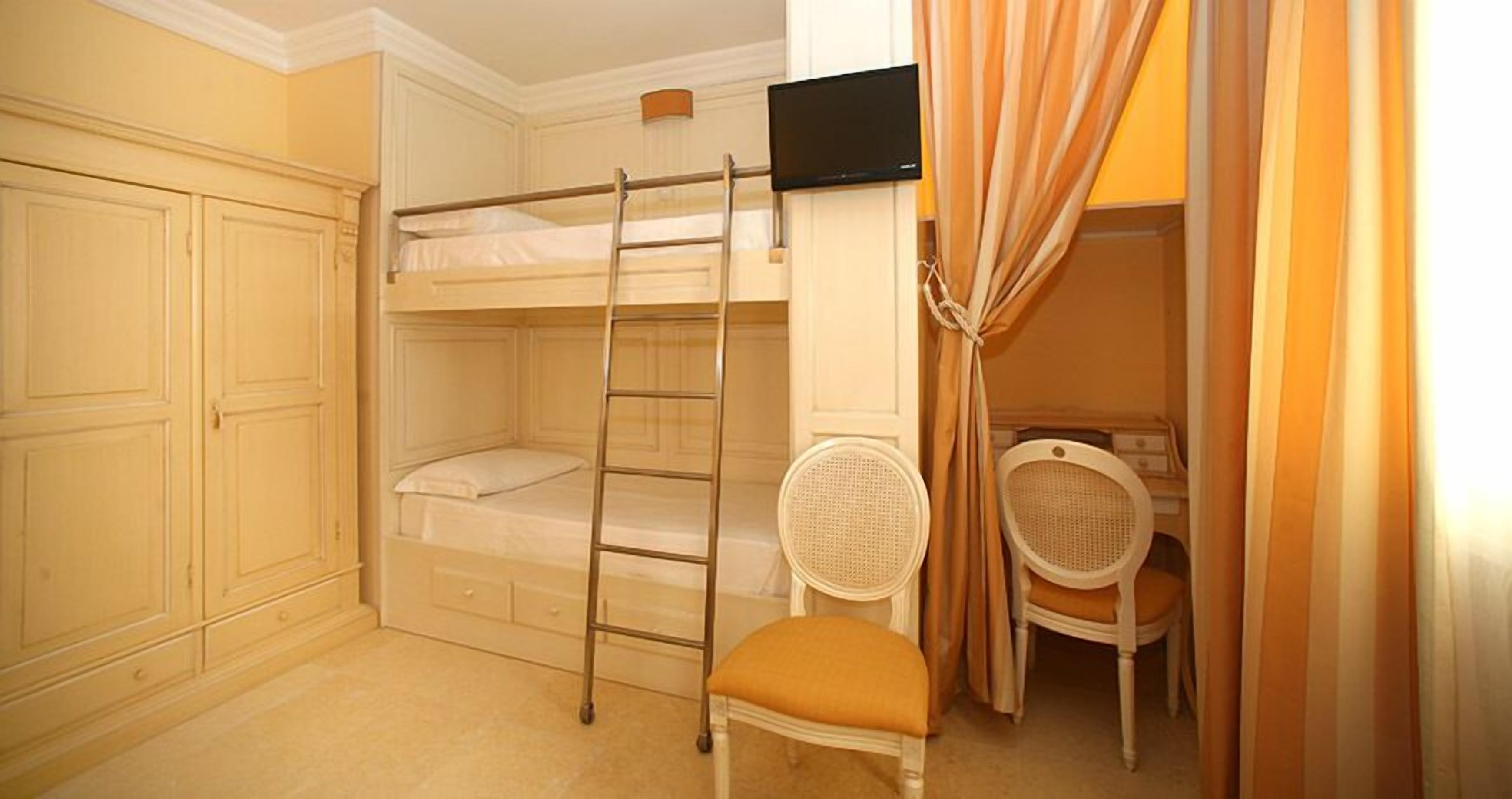 Un dormitorio con literas, un escritorio, una silla y un televisor.