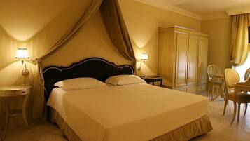 A hotel room with a large bed, two bedside tables, a wardrobe, a desk, and a chair.
