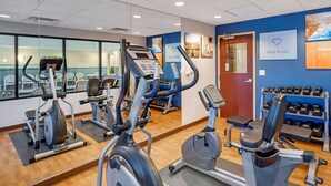 Un gimnasio con máquinas de cardio, bancos de pesas y mancuernas.
