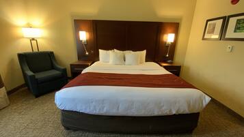 Una habitación de hotel con una cama grande, una silla, mesitas de noche y lámparas fijadas a la pared.