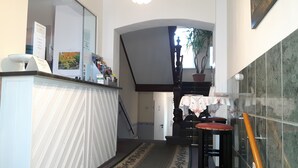 A staircase with a dark wooden handrail, a white wall with a door, and a tiled floor. - Hotel Plagwitzer Hof (Leipzig)