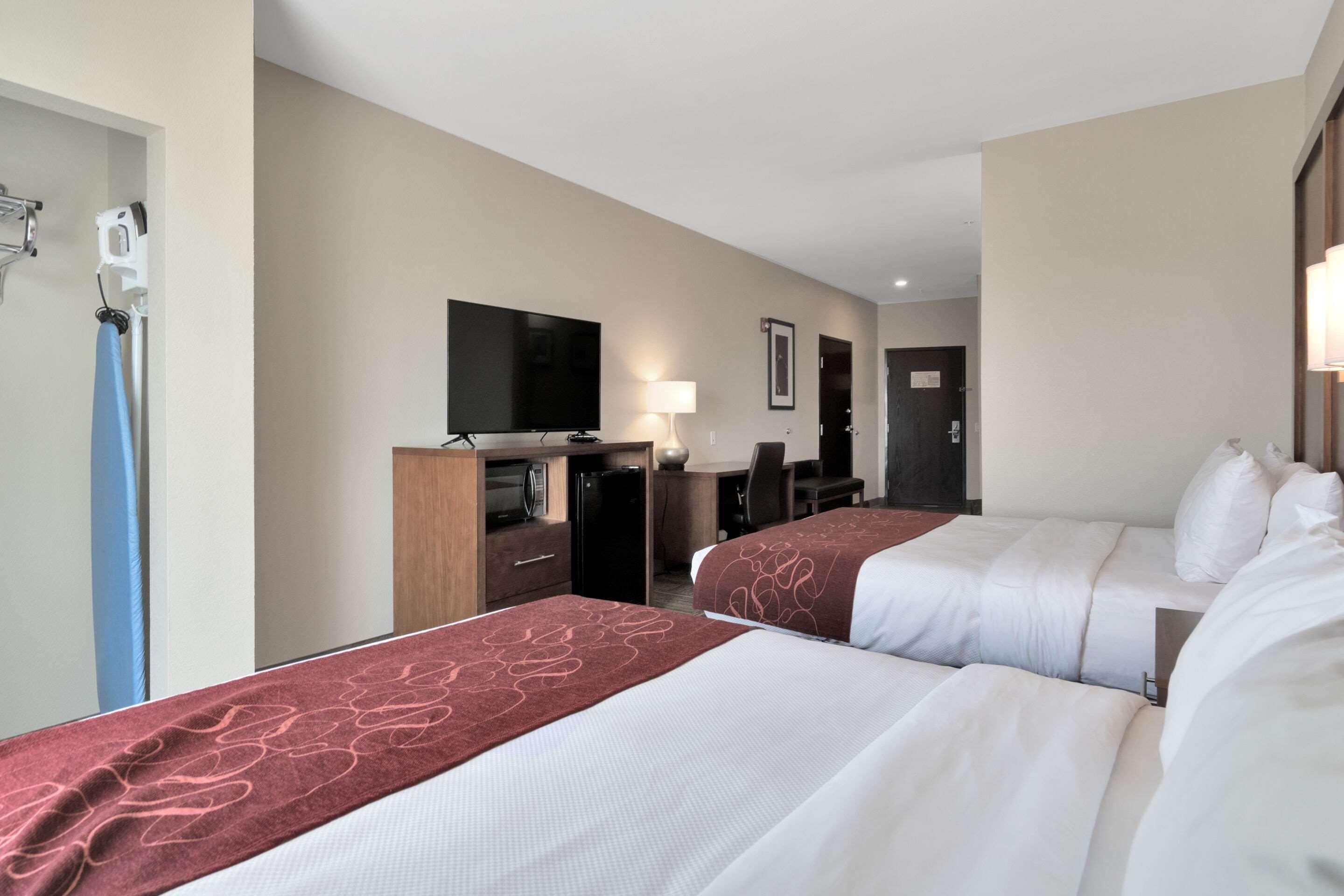 Une chambre d’hôtel avec deux lits, une télévision, un bureau et une armoire.