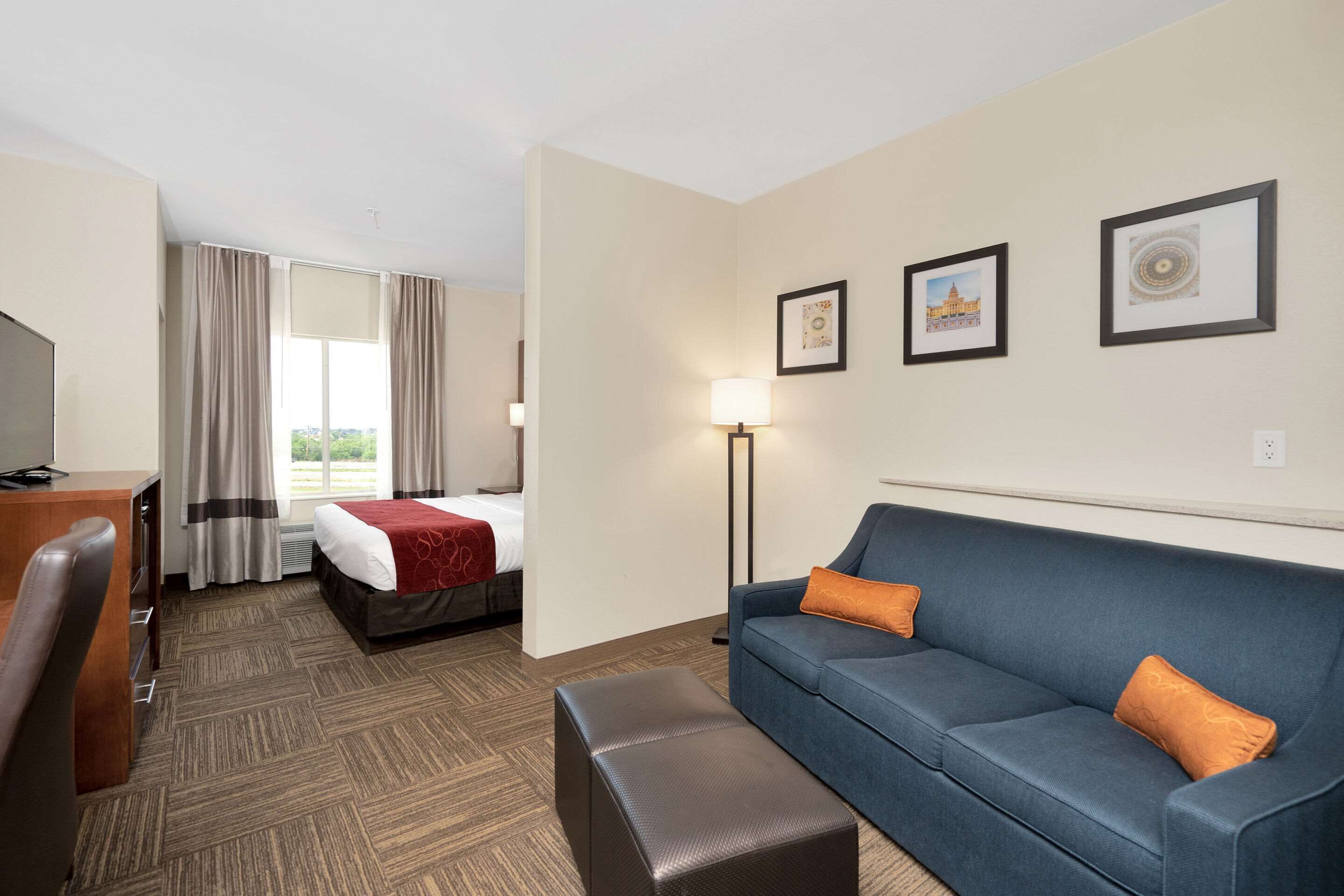 A hotel room with a bed, a desk, a sofa, and a lamp.