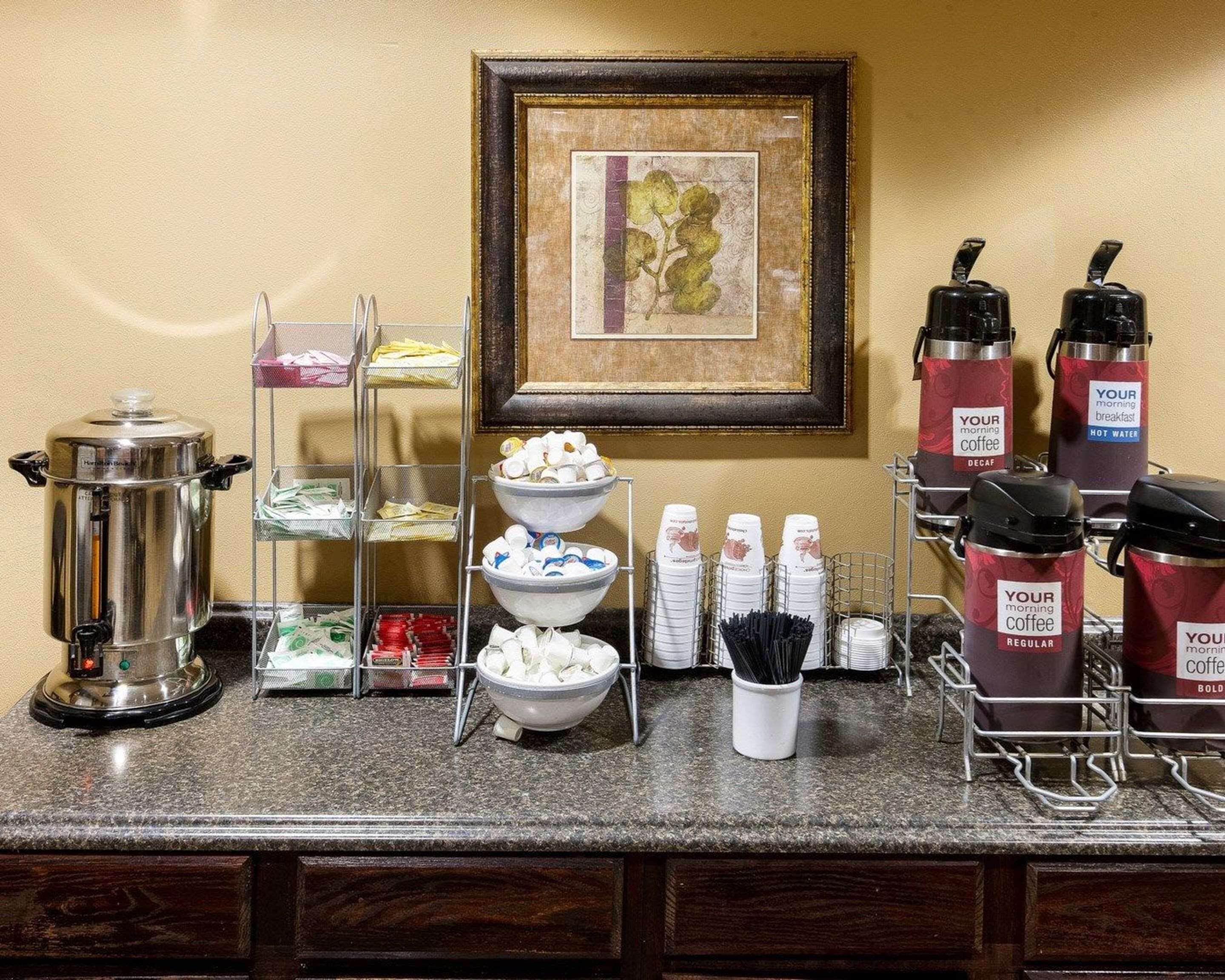 A buffet setup with a coffee station, including a coffee pot, cups, and a sign for 'Your morning coffee'.