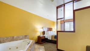 A hotel room with a large bathtub, a bed with two pillows, a nightstand with a lamp, and a window with curtains. - Comfort Inn & Suites Cedar City South (Cedar City)