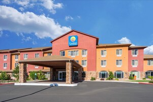 A Comfort Inn & Suites hotel with a covered entrance, multiple floors, and a clear sky.