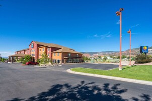A hotel with a red car parked in front, a parking lot, and a sign for a Comfort Inn.
