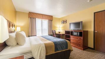 A hotel room with a bed, a desk, a television, and a wardrobe.