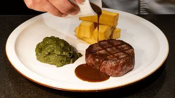 Un plato con bistecca, puré de papas y salsa verde.