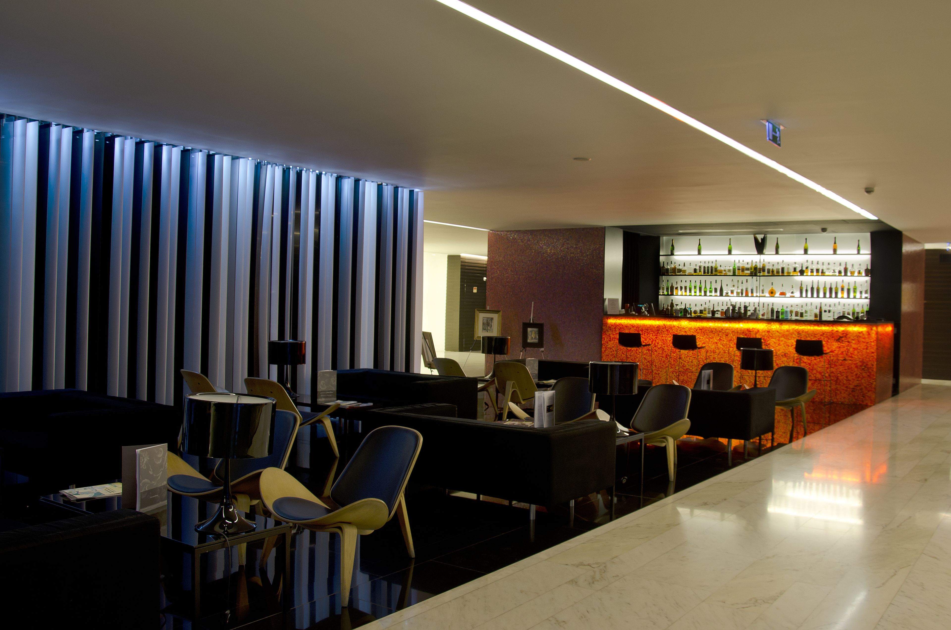 A modern bar area with a marble floor, seating arrangements, and a bar counter with various bottles.