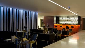 A modern bar area with a marble floor, seating arrangements, and a bar counter with various bottles.