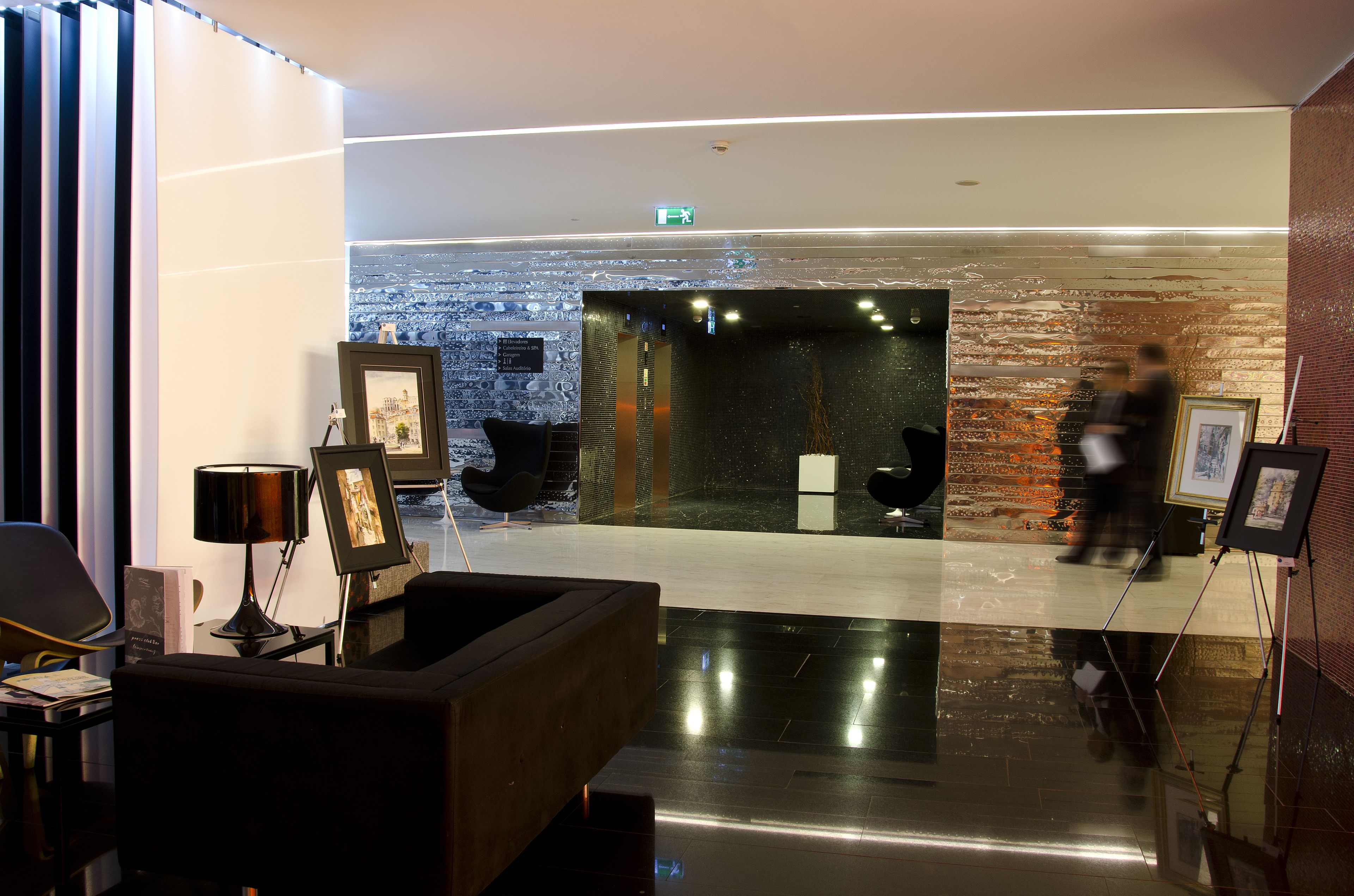 Een moderne lobby met een receptiebalie, een zithoek en kunstwerken.