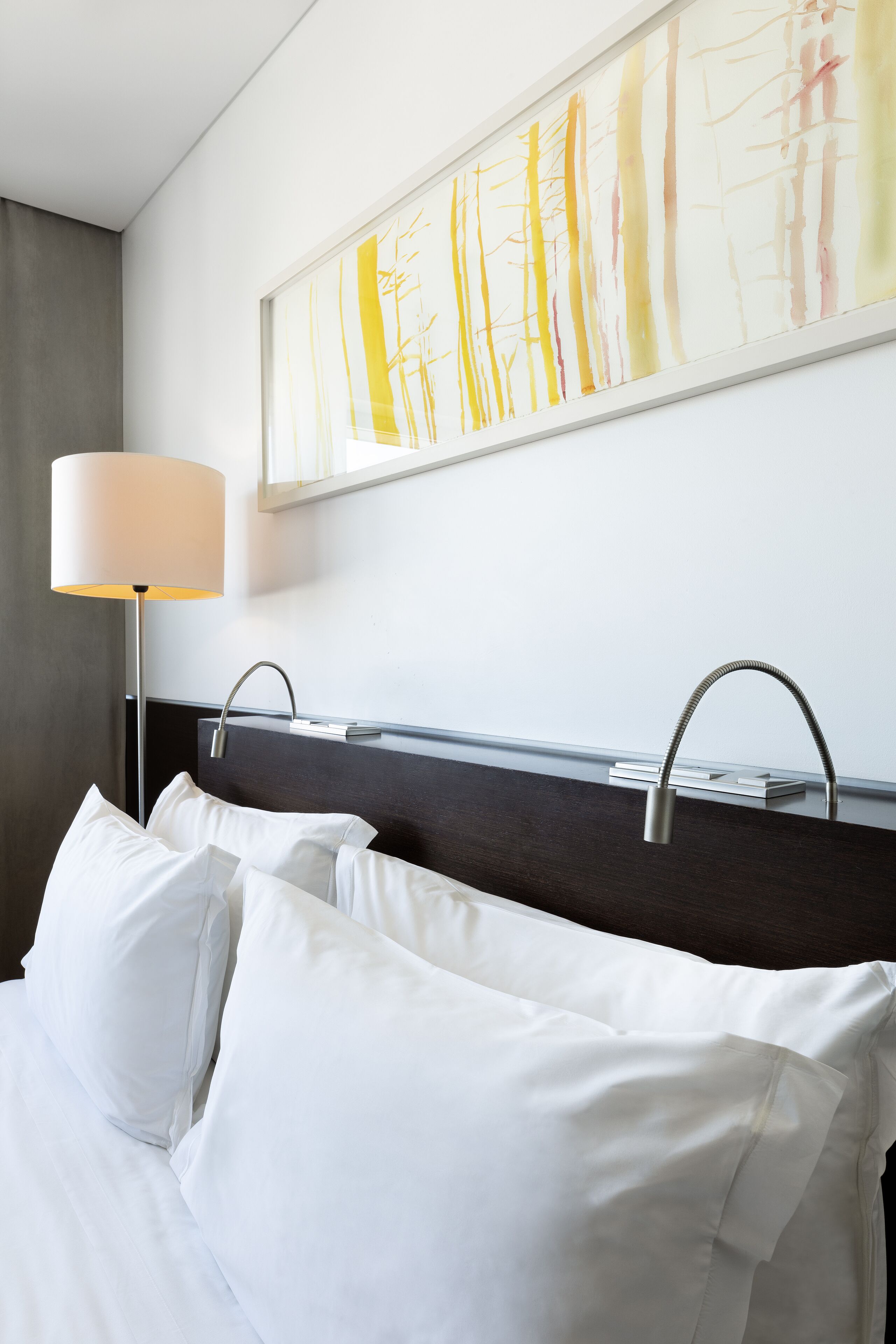 Ein Hotelzimmer mit einem Bett, einem Nachttisch, einer Lampe und einem Bild an der Wand.