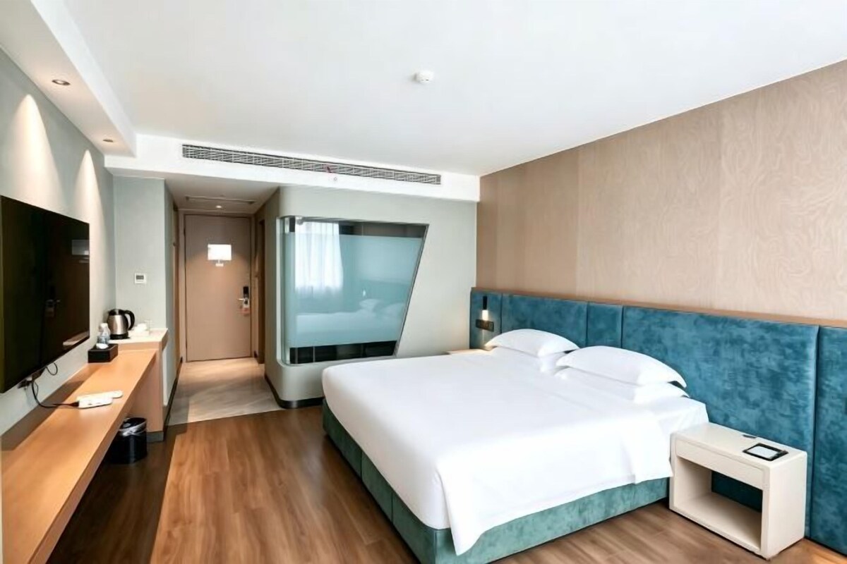 Une chambre d’hôtel comprenant un lit, une table de chevet, une télévision et un dressing.