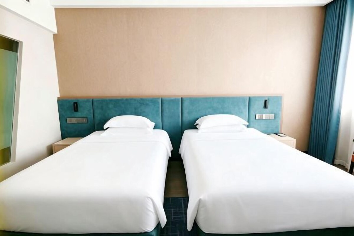 Une chambre d’hôtel avec deux lits simples, une tête de lit et une table de chevet.