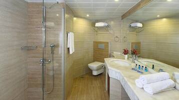 Un baño moderno con ducha envuelta en vidrio, inodoro y tocador con lavamanos y barra para toallas.