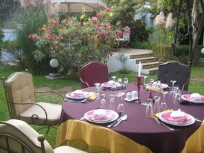Un espace de restauration en plein air avec une table dressée pour quatre personnes, entourée de chaises.