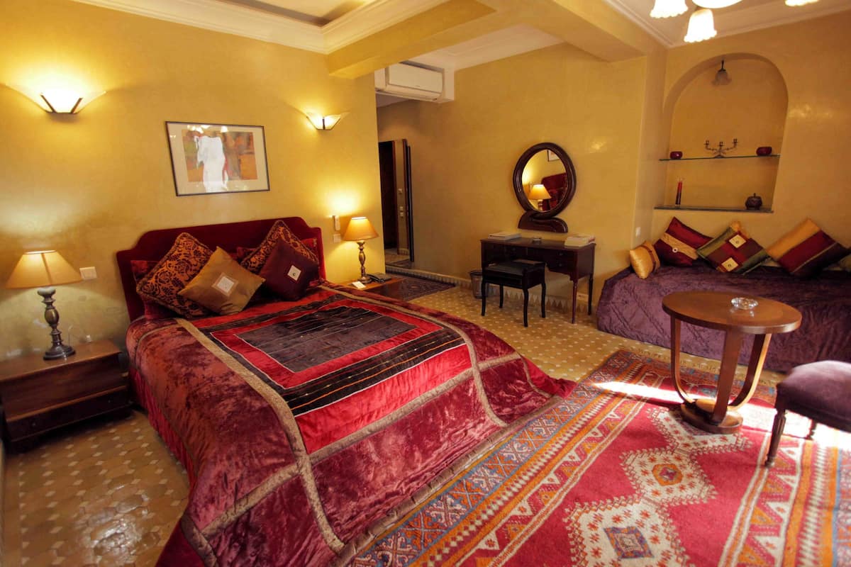 Una habitación de hotel con una cama grande, un escritorio, una silla, una mesa redonda y un espejo.