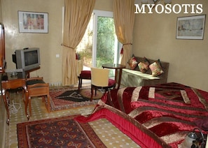 Une pièce confortable avec un lit, une télévision, une petite table et une chaise.