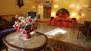 Una habitación con una cama, un sofá, un televisor y una mesa con un jarrón de flores.