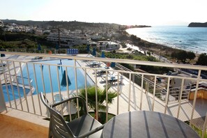 Un balcón con piscina, sillas y vista a la playa y al océano.