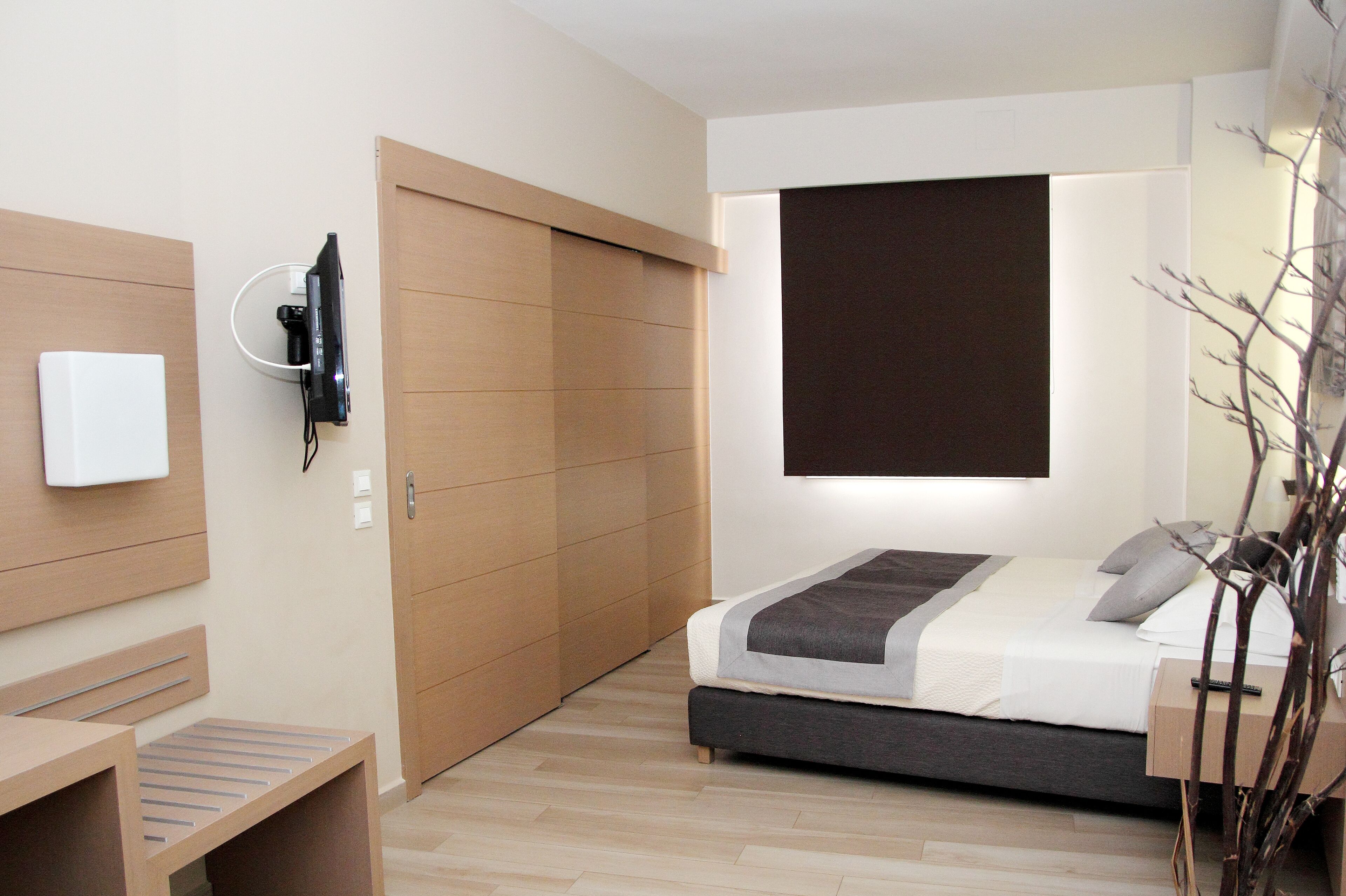 Un dormitorio moderno con cama, mesita de noche, televisor y armario.