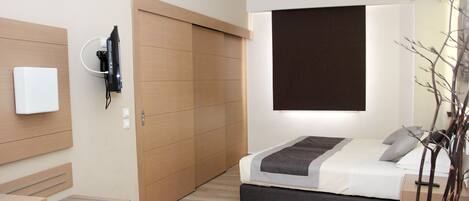 Un dormitorio moderno con cama, mesita de noche, televisor y armario.